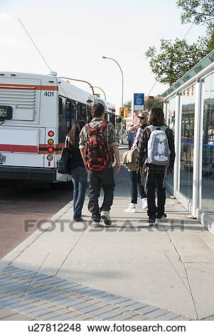 Stock Photo - Group of teens walking toward bus at transit shelter, Winnipeg, Manitoba, Canada. Fotosearch