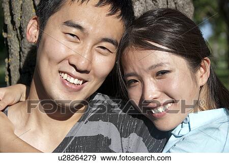 Stock Photo - Head shot of young couple stand beside tree in Assiniboine Park, Winnipeg, Canada. Fotosearch
