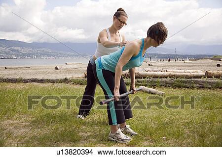 Picture - Instructor and woman practicing yoga on beach, Vancouver, BC. Fotosearch