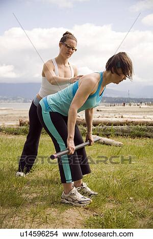 Picture - Instructor and woman practicing yoga on beach, Vancouver, BC. Fotosearch