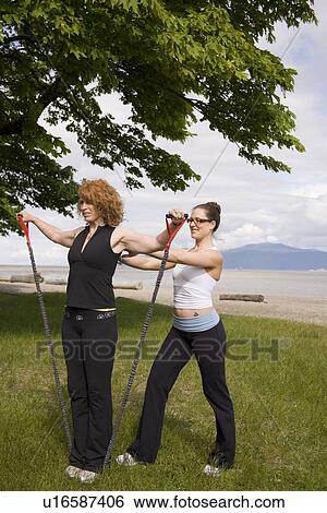 Stock Photograph - Instructor and woman practicing yoga on beach, Vancouver, BC. Fotosearch