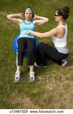Stock Photo - Instructor and woman using exercise ball on beach, Vancouver, BC. Fotosearch