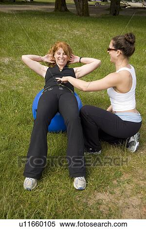Stock Photography - Instructor and woman using exercise ball on beach, Vancouver, BC. Fotosearch