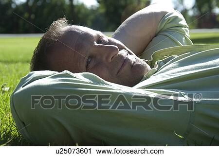 Man in 40's reclines in the grass in Assiniboine Park, Winnipeg, Canada View Large Photo Image Stock Image - Man in 40's reclines in the grass in Assiniboine Park, Winnipeg, Canada. Fotosearch