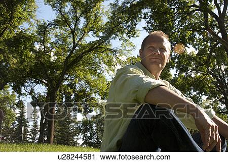 Man in 40's seated on grass in Assinboine Park, Winnipeg, Canada View Large Photo Image Stock Image - Man in 40's seated on grass in Assinboine Park, Winnipeg, Canada. Fotosearch