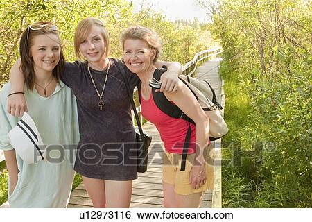 Stock Photograph - Mid-aged woman and two teen girls on nature boardwalk; Riding Mountain National Park; Clear Lake, Manitoba, Canada. Fotosearch
