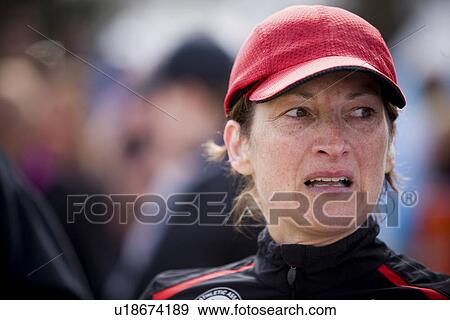 Stock Photo - Middle aged female runner with red cap catches her breath after race, Regina, Saskatchewan. Fotosearch