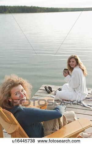 One woman seated in deck chair, second woman seated on dock with coffee, Clear Lake, Manitoba, Canada View Large Photo Image Stock Photo - One woman seated in deck chair, second woman seated on dock with coffee, Clear Lake, Manitoba, Canada. Fotosearch