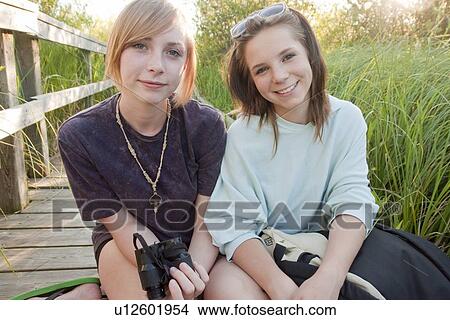 Picture - Portrait of two teens seated on boardwalk through marsh, Riding Mountain National Park, Manitoba, Canada. Fotosearch
