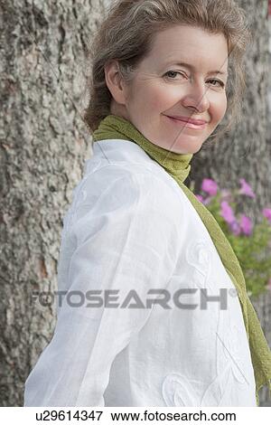 Stock Photo - Portrait of woman leaning against tree, Manitoba, Canada. Fotosearch