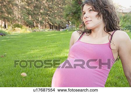 Picture - Pregnant woman seated on grass, Manitoba, Canada. Fotosearch