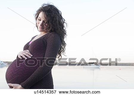 Pregnant woman with hands on abdomen, Clear Lake, Manitoba, Canada View Large Photo Image Stock Photo - Pregnant woman with hands on abdomen, Clear Lake, Manitoba, Canada. Fotosearch