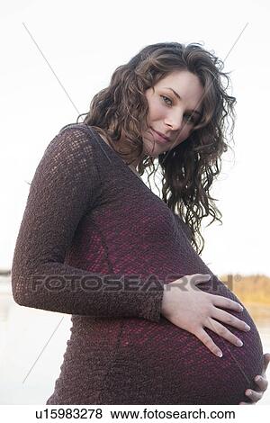 Stock Photo - Pregnant woman with hands on abdomen, Clear Lake, Manitoba, Canada. Fotosearch