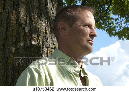 Profile of mani in 40's standing beside tree, Winnipeg, Canada View Large Photo Image Stock Image - Profile of mani in 40's standing beside tree, Winnipeg, Canada. Fotosearch