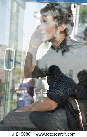 Profile of teen using cell phone behind glass of transit shelter, Winnipeg, Manitoba, Canada View Large Photo Image Stock Image - Profile of teen using cell phone behind glass of transit shelter, Winnipeg, Manitoba, Canada. Fotosearch