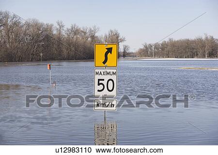 Stock Image - Road sign is rather pointless now that the road is covered with floowater from the Red River, rural Manitoba. Fotosearch