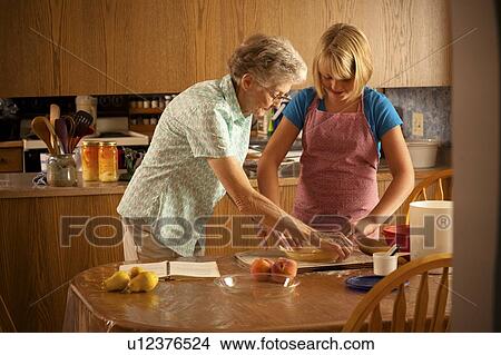 Senior woman and her twelve year old great granddaughter place pastry in pie plate; Redvers, Saskatchewan, Canada View Large Photo Image Picture - Senior woman and her twelve year old great granddaughter place pastry in pie plate; Redvers, Saskatchewan, Canada. Fotosearch