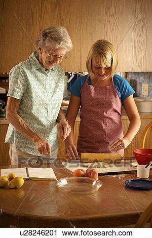 Stock Image - Senior woman and her twelve year old great granddaughter baking; Redvers, Saskatchewan, Canada. Fotosearch