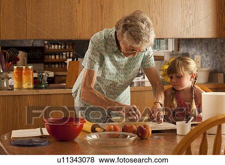 Stock Photo - Senior woman and little girl placing pastry in pie plate, Redvers, Saskatchewan, Canada. Fotosearch