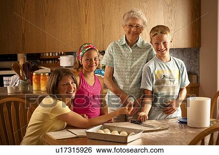 Stock Photograph - Senior woman, grandaughter and 2 great grandchildren preparing buns to bake; Redvers, Saskatchewan, Canada. Fotosearch