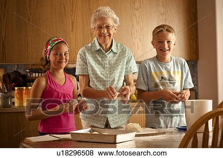 Stock Photo - Senior woman preparing buns with her great grandchildren; Redvers, Saskatchewan, Canada. Fotosearch