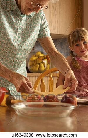 Stock Photo - Senior woman with pastry, great grand daughter smiling at camera; Redvers, Saskatchewan, Canada. Fotosearch