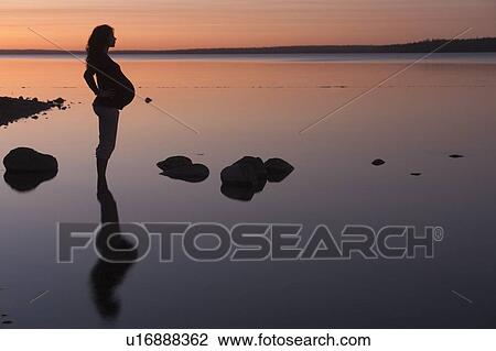 Stock Image - Silohuette of pregnant woman at sunset, Clear Lake, Manitoba, Canada. Fotosearch