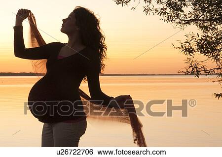 Stock Photograph - Silohuette of pregnant woman at sunset, Clear Lake, Manitoba, Canada. Fotosearch