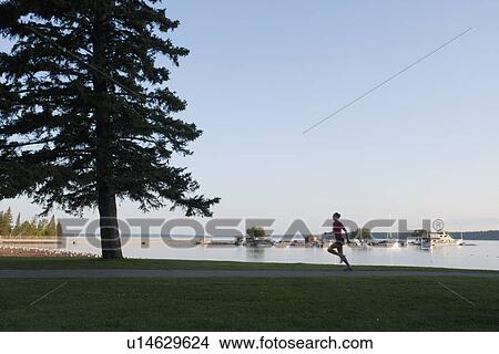 Picture - Silohuette of woman running by lakeshore, Clear Lake, Riding Mountain National Park, Manitoba, Canada. Fotosearch