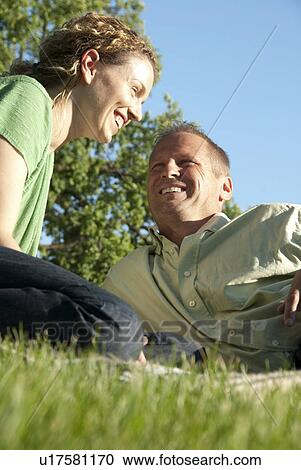 Stock Image - Smiling couple seated on grass in Assiniboine Park, Winnipeg, Canada. Fotosearch
