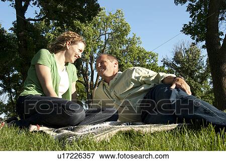 Stock Photo - Smiling couple seated on grass in Assiniboine Park, Winnipeg, Canada. Fotosearch