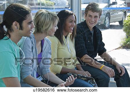 Stock Photograph - Teens standing beside bus schedules on street, Winnipeg, Maniotba, Canada. Fotosearch