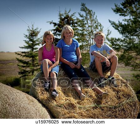 Three tween kids seated on bale, Redvers, Saskatchewan, Canada View Large Photo Image Stock Photography - Three tween kids seated on bale, Redvers, Saskatchewan, Canada. Fotosearch