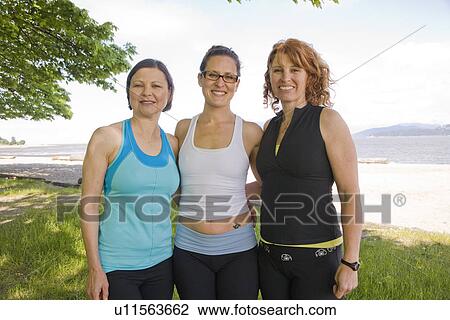 Stock Image - Three women in yoga wear at beach park, Vancouver, BC. Fotosearch
