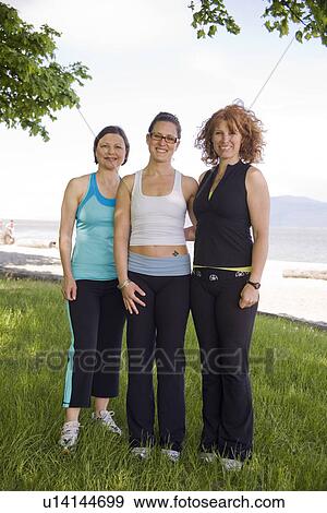 Stock Photo - Three women in yoga wear at beach park, Vancouver, BC. Fotosearch