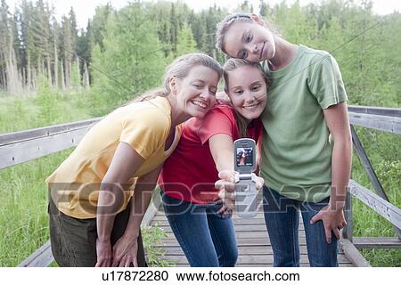 Stock Image - Three women on boardwalk nature trail take picture with cell phone, Riding Mountain National Park, Manitoba, Canada. Fotosearch