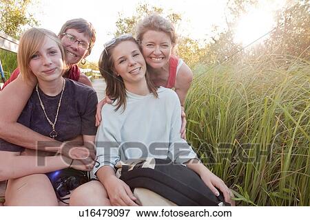 Stock Photo - Two moms and two teens posing on boardwalk in marsh, Riding Mountain National Park, Manitoba, Canada. Fotosearch