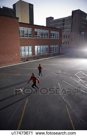 Stock Image - Two runners and dog very early morning in urban parking lot, Regina Saskatchewan. Fotosearch