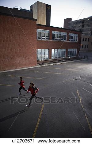 Stock Image - Two runners sprinting, very early morning in urban parking lot, Regina Saskatchewan. Fotosearch