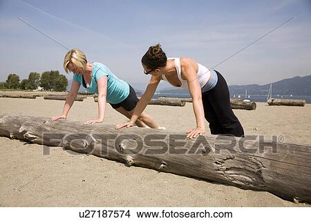 Two women doing push-ups on log at beach, Vancouver, BC View Large Photo Image Picture - Two women doing push-ups on log at beach, Vancouver, BC. Fotosearch