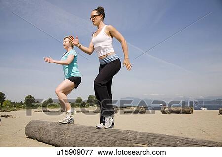 Stock Photo - Two women doing step ups on log at beach, Vancouver, BC. Fotosearch