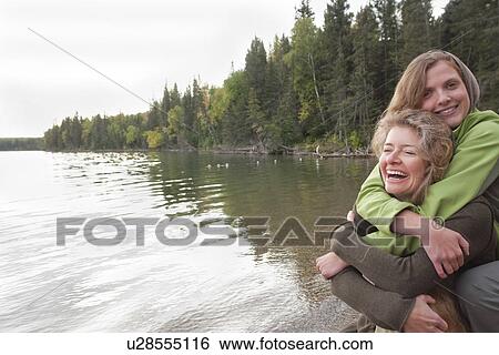 Stock Photograph - Two women embrace at shoreline, Clear Lake, Manitoba, Canada. Fotosearch