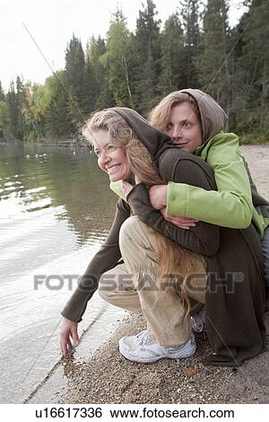 Two women on haunches by shore of lake, Clear Lake, Manitoba View Large Photo Image Stock Photograph - Two women on haunches by shore of lake, Clear Lake, Manitoba. Fotosearch