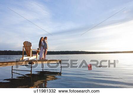 Stock Image - Two women standing on dock, with deck chair, Clear Lake, Manitoba, Canada. Fotosearch