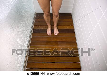 Picture - View of woman's feet in steamy shower stall with low flow faucet.. Fotosearch