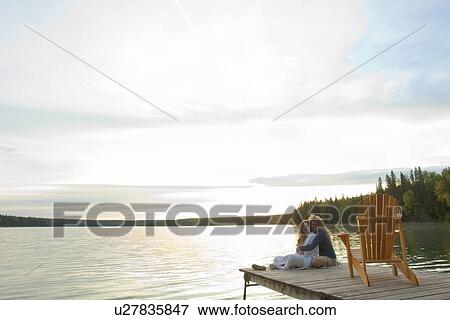 Stock Photo - Vista of Clear lake with mom and adult daughter seated on dock, Clear Lake, Manitoba, Canada. Fotosearch