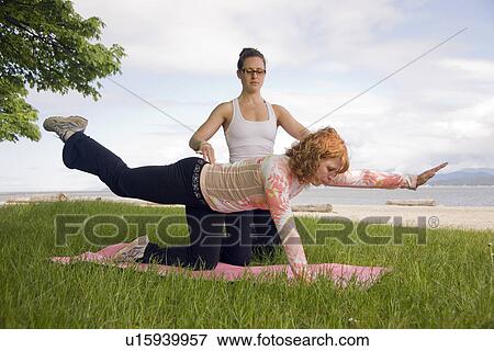 Stock Photo - Woman and instructor doing yoga in park, Vancouver, BC. Fotosearch