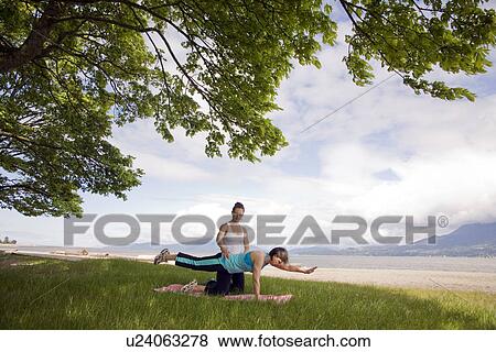 Stock Photo - Woman and instructor doing yoga in park, Vancouver, BC. Fotosearch