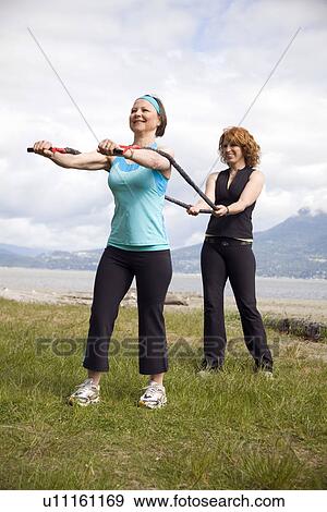 Stock Photo - Woman and instructor using yoga bands on beach, Vancouver, BC. Fotosearch