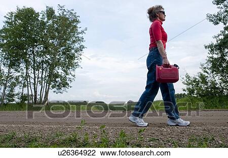 Woman holding gas can walks along gravelled country road, Manitoba, Canada View Large Photo Image Stock Image - Woman holding gas can walks along gravelled country road, Manitoba, Canada. Fotosearch